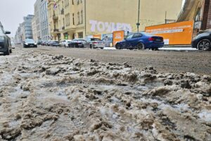 Wetterbericht für Schleswig-Holstein/Hamburg (17.02.2026) Schneematsch auf einer winterlichen Straße, graue Wolken und frostige Temperaturen.